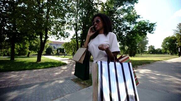 一个女人拿着购物袋走在城市公园里