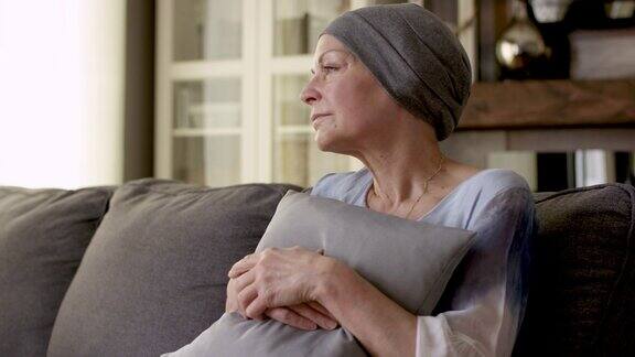 一位身患癌症的妇女坐在家里的沙发上