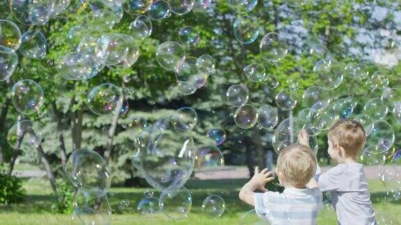 在公园的泡泡表演中男孩们抓住巨大的肥皂泡
