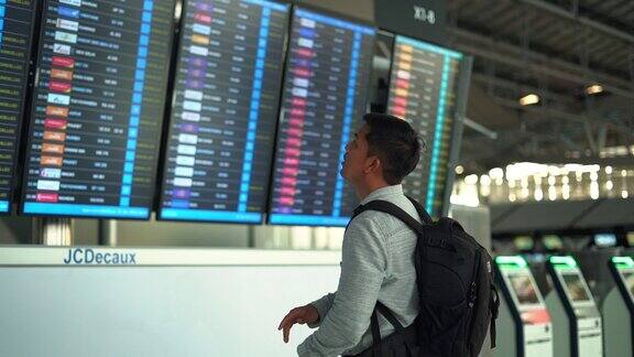 旅客在机场候机楼查看航班时刻表