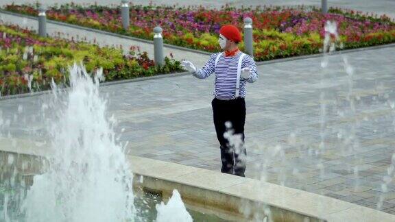 戴着红色贝雷帽的哑剧演员和喷泉玩得很开心