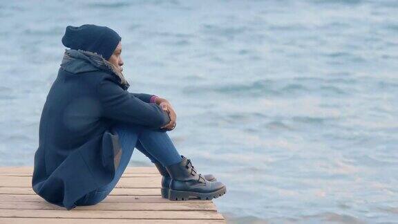 悲伤孤独孤独的黑女人坐在码头上思考