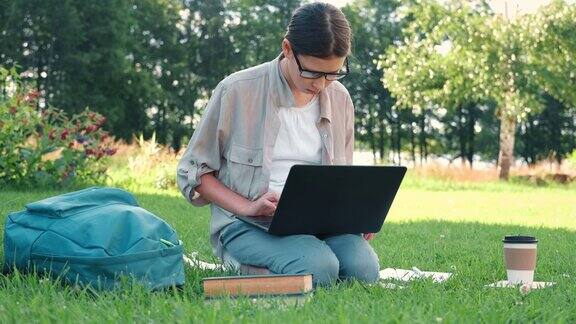 十几岁的女学生坐在户外读书看她的书平板电脑和笔记本回到学校在校园里或公园里女学生躺在草地上使用笔记本电脑远程学习