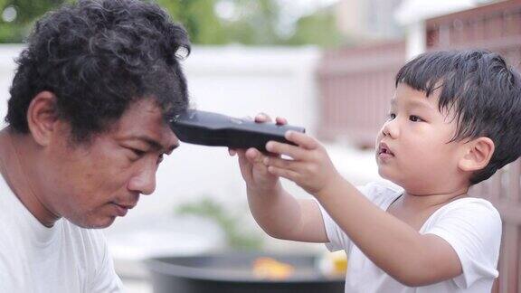 新冠肺炎大流行期间儿子在家用电动剃须刀给父亲理发