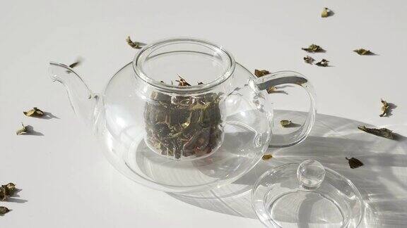 茶叶落在白桌上的玻璃茶壶里的超级慢动作