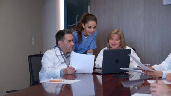 医生和护士小组讨论一个病例同时在笔记本电脑上查看病人的病历