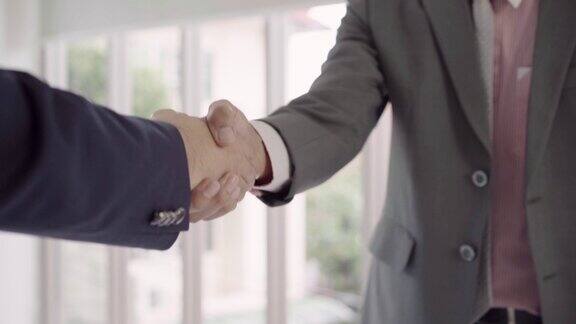 慢动作在招聘会议后握手以达成协议两个自信的亚洲商人在办公室开会时握手成功交易问候和合作伙伴