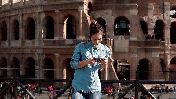 一名女游客在看智能手机里的建筑物照片意大利罗马斗兽场的背景慢动作