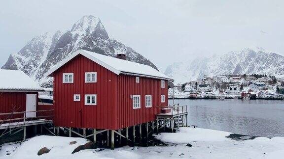 挪威罗浮敦群岛勒内(Reine)的北极海岸线上有雪和山的红色房子