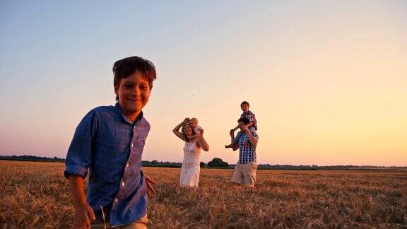 日落时分可爱的一家人在麦田里散步