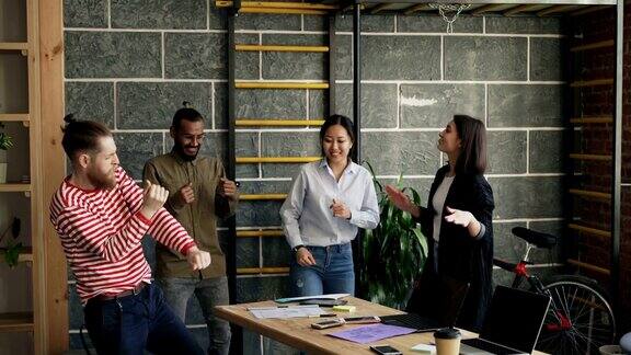 多民族创业公司的同事在现代的办公室里跳舞扔文件庆祝项目的成功