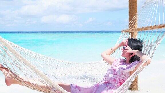 美丽的女人躺在热带海滩的吊床上