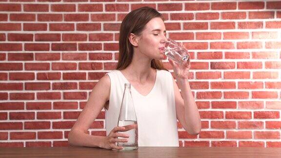 一个年轻漂亮的女人从玻璃杯里喝水