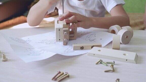 一个男孩在家里的木桌上用螺丝刀组装木制玩具车