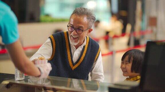 亚洲华人祖父孙女在电影院吧台买爆米花娱乐大厦的小卖部电影院电影院