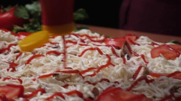 把番茄酱倒在披萨上特写镜头框架特写的手在披萨上洒酱汁