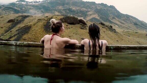 冰岛的地热温泉两个旅游的女人在温泉中放松与美丽的风景在山上