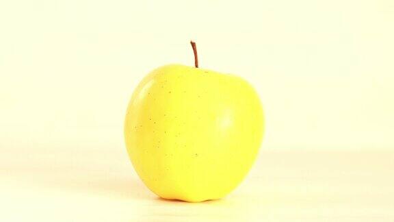 黄色的苹果在白色的背景上旋转-停止运动的镜头