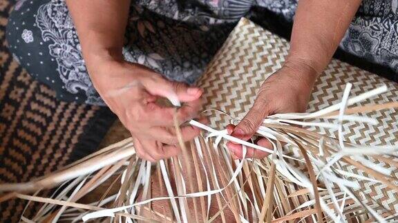 特写的妇女编织一个干叶编织篮子篮子的手工工艺生产