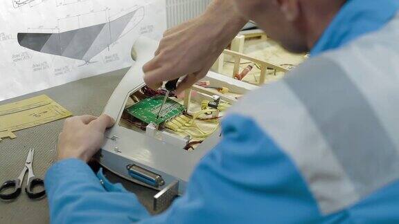 工业实验室无人驾驶飞行器的人工装配男工程师在机身上安装电子设备生产商用空中侦察或军用飞机