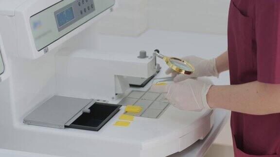 实验室助理进行组织切片检查用于病理诊断的旋转切片机的切片制成组织学显微镜载玻片给组织样本打蜡