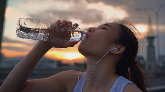 年轻的亚洲女运动员跑步后喝水慢动作