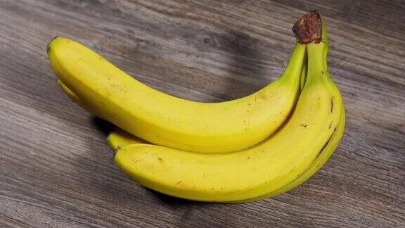 一串成熟的黄色香蕉在木制背景上顺时针旋转甜的水果