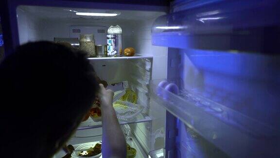 在冰箱里找食物的人一个没刮胡子的男人在他的冰箱里挖洞试着吃剩菜然后关上它