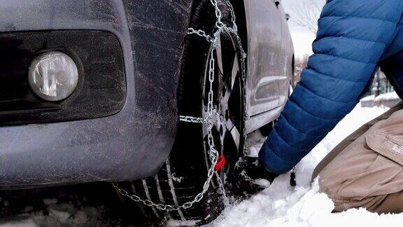 困在雪中的汽车和在轮胎上装雪链的人