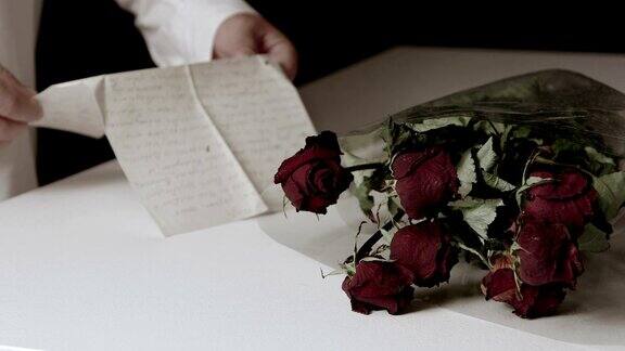 桌上放着一束枯萎的玫瑰男人正在读告别信