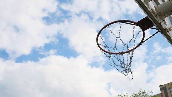 篮球场上的篮筐和篮球的侧视图背景是天空和云彩