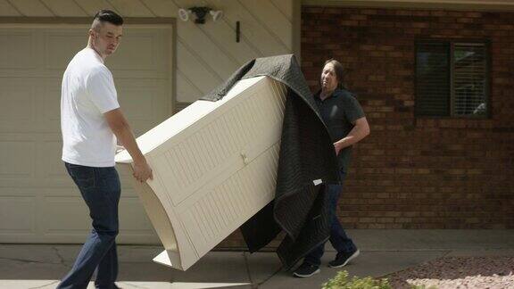 两个男人把家具搬到搬家车上