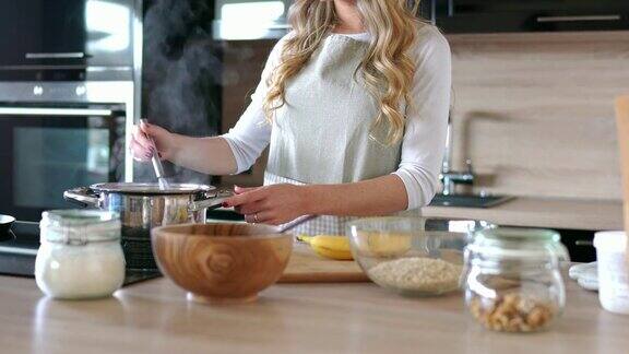 金发女人在厨房做早餐燕麦粥