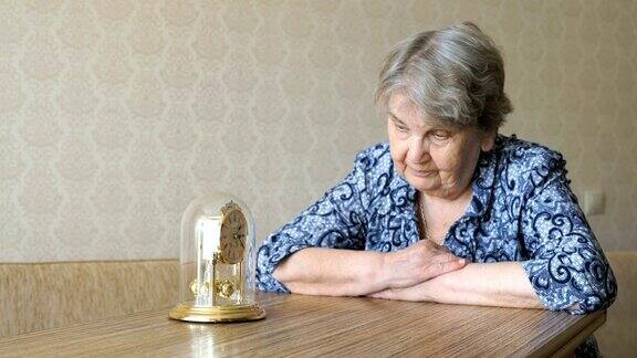 老妇人用钟摆看着桌子上的钟