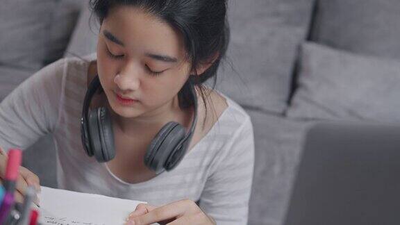 近距离拍摄4k分辨率迷人的亚洲少女戴着耳机和她的老师在笔记本电脑屏幕上学习在线家庭学校而冠状病毒或冠状病毒19封锁视频电话和她的建议学习她的家庭作业