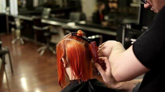 年轻女子在美发沙龙做头发Stylist-hairdresser在起作用美发师在美容院梳头在slowmotion拍摄