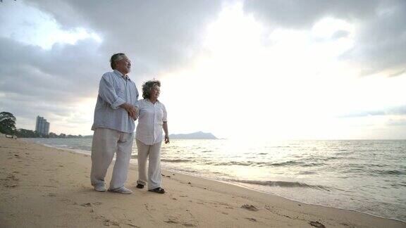 亚洲老夫妇散步和聊天在美丽的热带海滩在慢动作