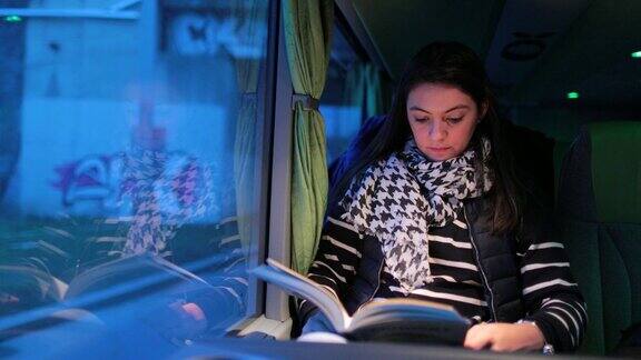 年轻女子读书而旅行的公共汽车在道路上在4k