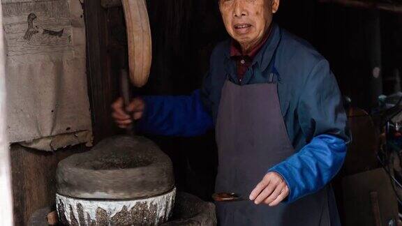 在中国古老的木质谷仓里碾磨谷物的工人