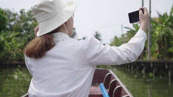 一个美丽的亚洲女人旅行和拍照在出租船上度假周末