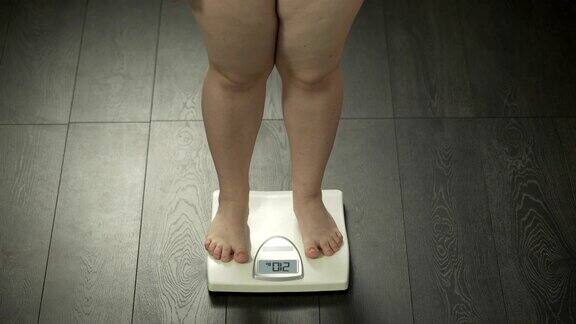 超重的女性踩在浴室秤上健康失调肥胖