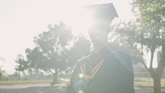 一名年轻的男学生双臂交叉站在一所大学外面看起来很开心一个骄傲的人看起来很高兴在一所大学外面庆祝他的毕业