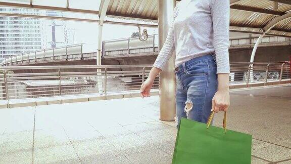 女人提着购物袋在城市里走来走去