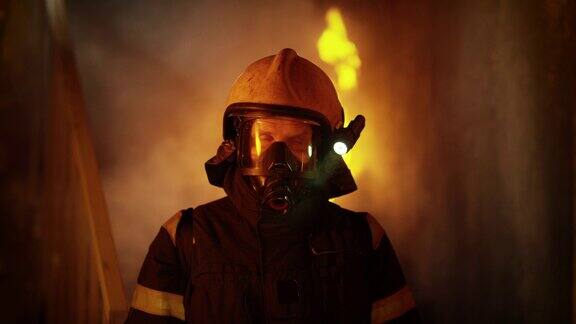 一名勇敢的消防员站在燃烧的大楼里背景中的熊熊大火