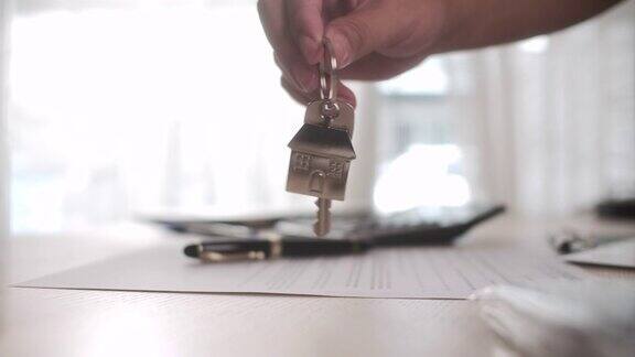 在一个房子形状的钥匙圈上拿着新房子的钥匙