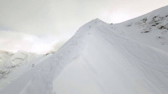 鸟瞰图运动FPV无人机飞上山山脊与人从顶部骑上滑雪板