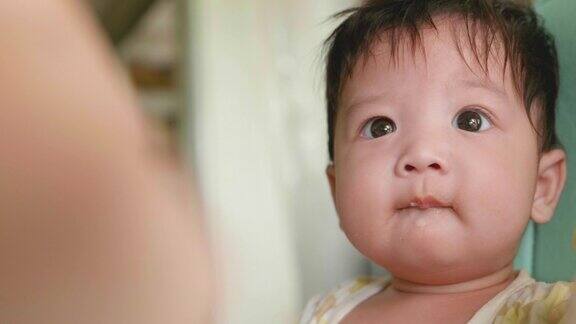 可爱的亚洲宝宝在椅子上吃婴儿食品