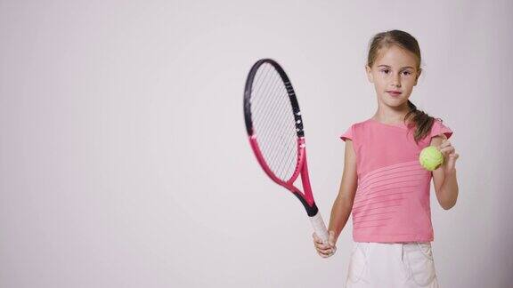 年轻的女网球运动员穿粉色运动服的女孩在弹球