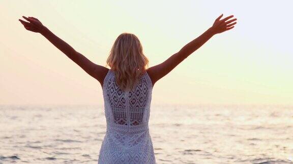 日落时分海滩上的女人举起手