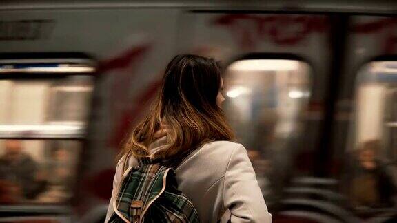 黑发女人站在火车站等待她的火车晚上在地铁里的女孩看快速电车